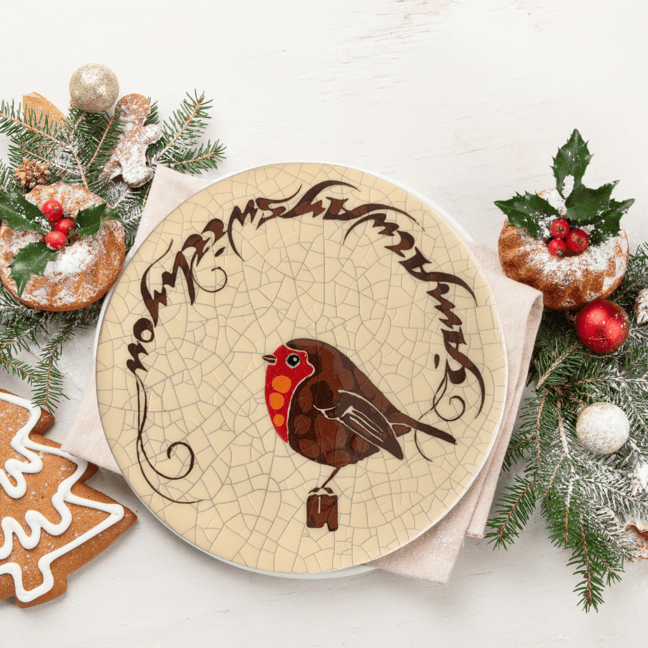 Robin on ceramic tile surrounded by Christmas decorations.