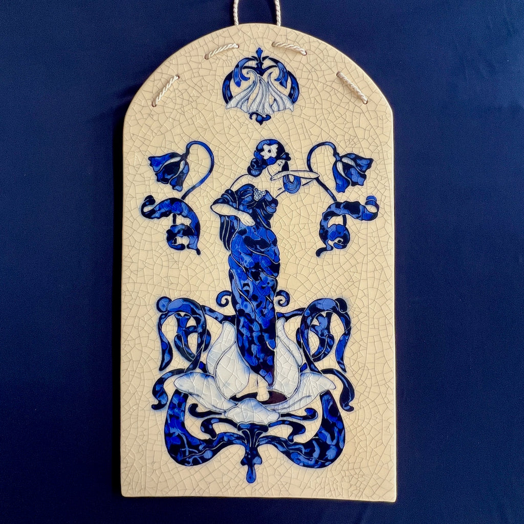 Decorative ceramic hand carved tile with blue Art Nouveau Lady surrounded by a floral design with a crackle glaze background.