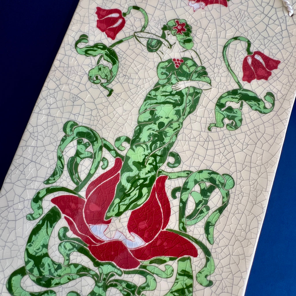 Decorative ceramic hand carved tile with green and red Art Nouveau Lady surrounded by a floral design with a crackle glaze background.