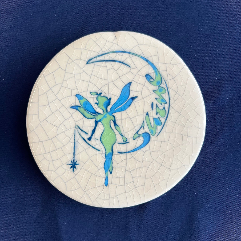 Round ceramic coaster with fairy design on a blue background