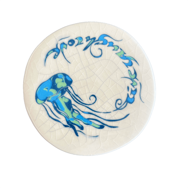 Round white coaster with blue jellyfish design on a crackle glaze background